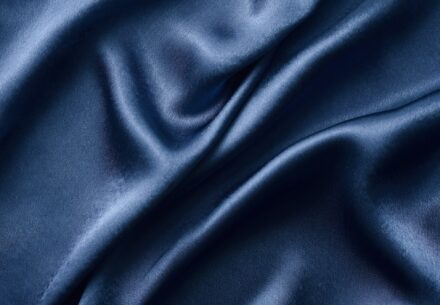 Silver silk background with a folds. Abstract texture of rippled silk surface